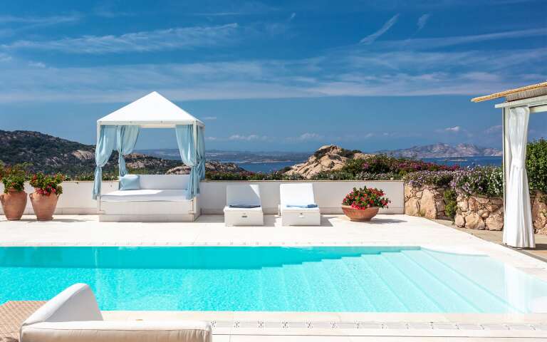 infinity swimming pool with covered sunbeds and sea view